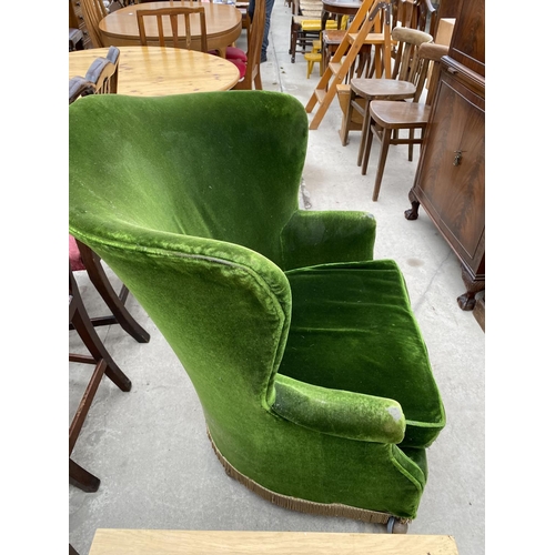 2375 - AN EDWARDIAN GREEN UPHOLSTERED ROUNDED WING-BACK EASY CHAIR ON CASTERS