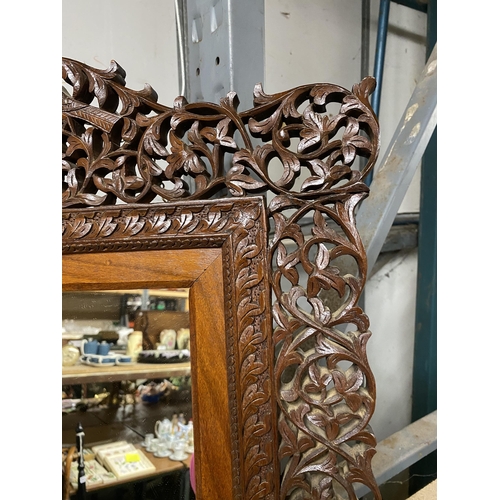 1075 - A 20TH CENTURY HARDWOOD WALL MIRROR WITH CARVED FOLIATE AND ANIMAL AND BIRD DECORATION 69CM X 56CM