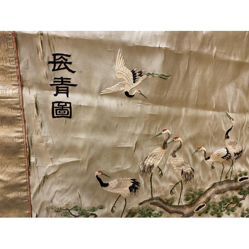 385 - AN ORIENTAL SILK HANGING DEPICTING STORKS IN A GARDEN LANDSCAPE 70 X 92CM