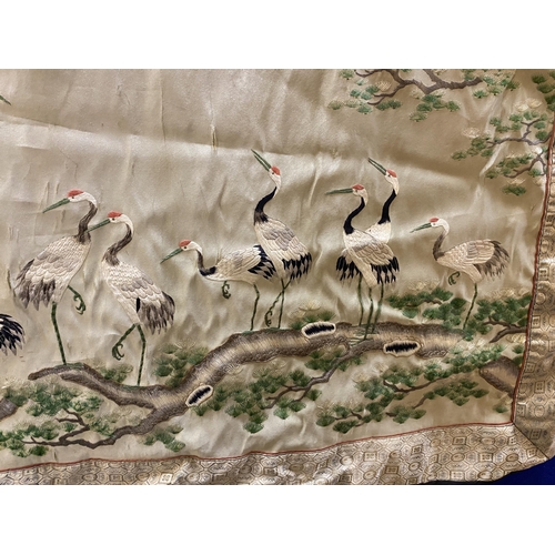 385 - AN ORIENTAL SILK HANGING DEPICTING STORKS IN A GARDEN LANDSCAPE 70 X 92CM