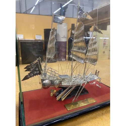 37 - A PRESENTATION SILVER EFFECT WHITE METAL MODEL OF A BOAT IN  A GLASS DISPLAY CASE