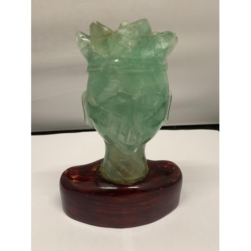102 - A BUST OF A REGAL STYLE FIGURE IN GREEN STONE ON A WOODEN BASE HEIGHT 19CM