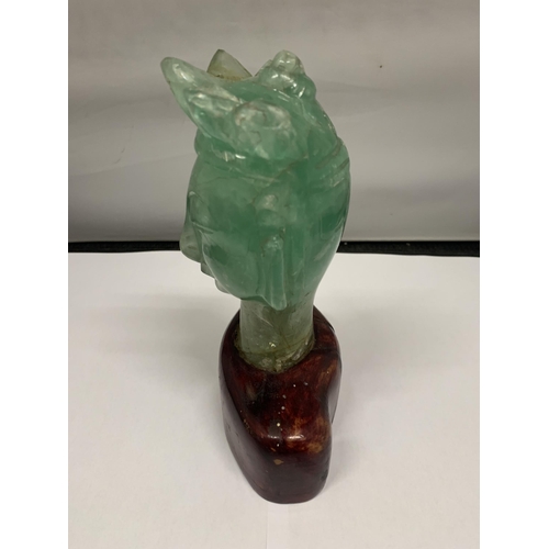 102 - A BUST OF A REGAL STYLE FIGURE IN GREEN STONE ON A WOODEN BASE HEIGHT 19CM