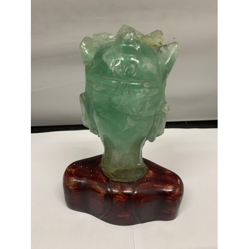 102 - A BUST OF A REGAL STYLE FIGURE IN GREEN STONE ON A WOODEN BASE HEIGHT 19CM