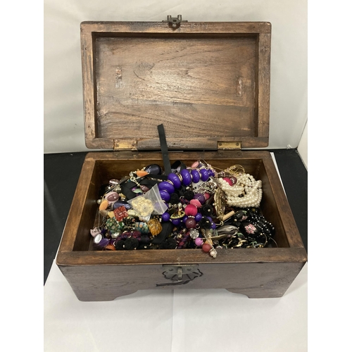 134 - A VINTAGE MAHOGANY BOX CONTAINING A QUANTOITY OF COSTUME JEWELLERY TO INCLUDE NECKLACES, BRACELETS, ... 