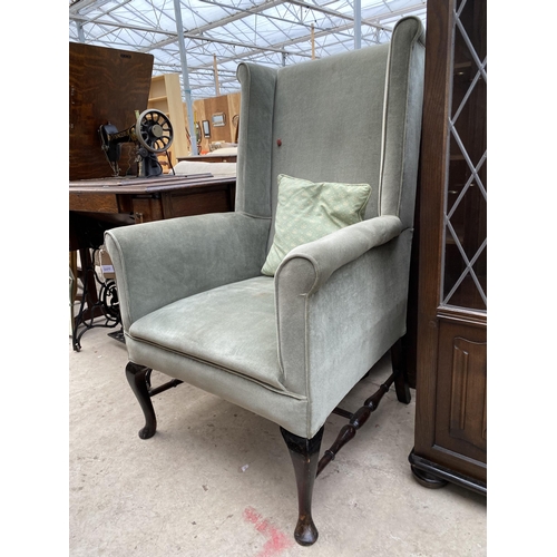 2377 - A SPRUNG AND UPHOLSTERED WINGED FIRESIDE CHAIR ON FRONT CABRIOLE LEGS WITH TURNED STRETCHERS