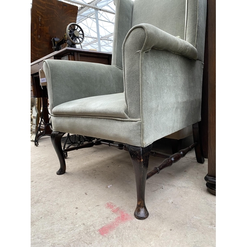 2377 - A SPRUNG AND UPHOLSTERED WINGED FIRESIDE CHAIR ON FRONT CABRIOLE LEGS WITH TURNED STRETCHERS