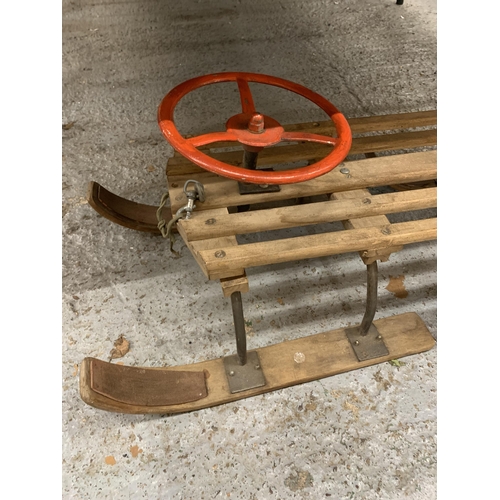 243 - A VINTAGE WOODEN SLEDGE WITH A STEERING WHEEL