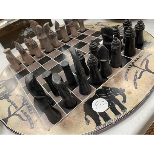 277 - A STONE CHESS BOARD AND PIECES WITH AFRICAN ANIMALS DESIGN AND STONE CHESS PIECES