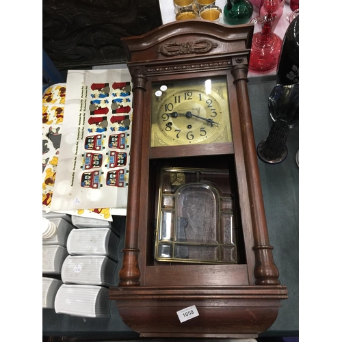 1058 - A MAHOGANY FRAMED WALL CLOCK WITH BEVELLED GLASS DOOR, PENDULUM AND KEY IN NEED OF SOME RESTORATION ... 