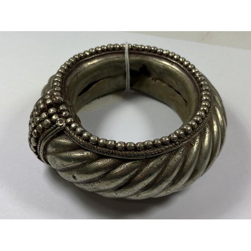 648 - A VINTAGE TRIBAL ORNATE BANGLE, TESTED SILVER