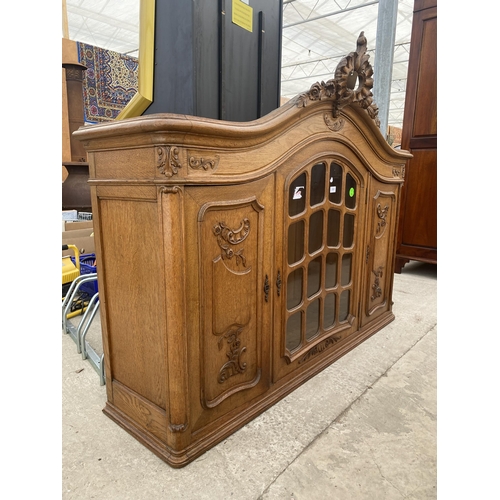 2885 - A CONTINENTAL OAK GLAZED CABINET WITH CARVED PANEL DOORS