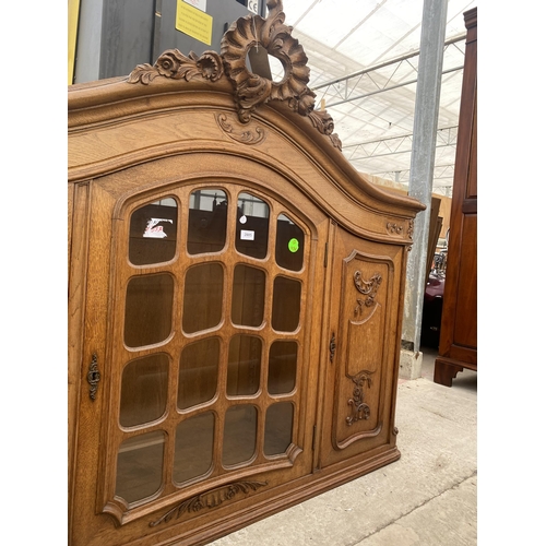 2885 - A CONTINENTAL OAK GLAZED CABINET WITH CARVED PANEL DOORS