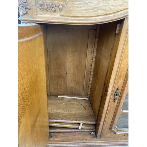 2885 - A CONTINENTAL OAK GLAZED CABINET WITH CARVED PANEL DOORS