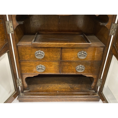 69 - A VINTAGE OAK SMOKERS CABINET WITH CHERUB DESIGN CIRCULAR PLAQUES, INNER DRAWERS AND PULL OUT TRAY, ... 