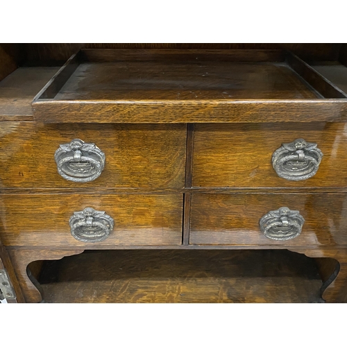 69 - A VINTAGE OAK SMOKERS CABINET WITH CHERUB DESIGN CIRCULAR PLAQUES, INNER DRAWERS AND PULL OUT TRAY, ... 