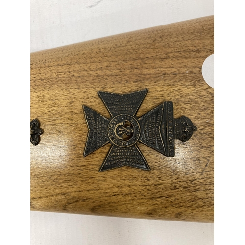 131 - A RIFLE BUTT WITH ATTACHED MILITARY BADGES