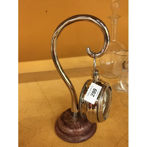 299 - A CHROME POCKET WATCH STYLE CLOCK ON A CHROME STAND WITH WOODEN BASE