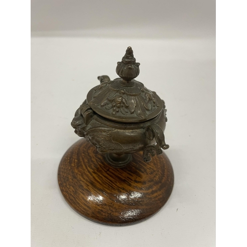 10 - A TWIN HANDLED BRONZE LIDDED INKWELL ON OAK BASE