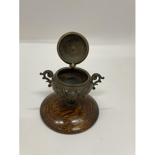 10 - A TWIN HANDLED BRONZE LIDDED INKWELL ON OAK BASE