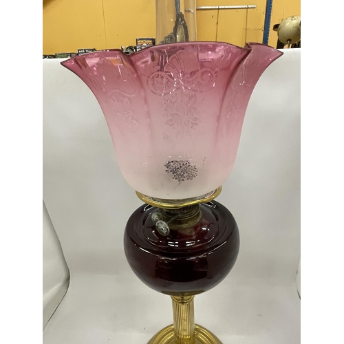 35 - AN EARLY TO MID 20TH CENTURY BRASS CORINTHIAN COLUMN OIL LAMP WITH CRANBERRY GLASS SHADE