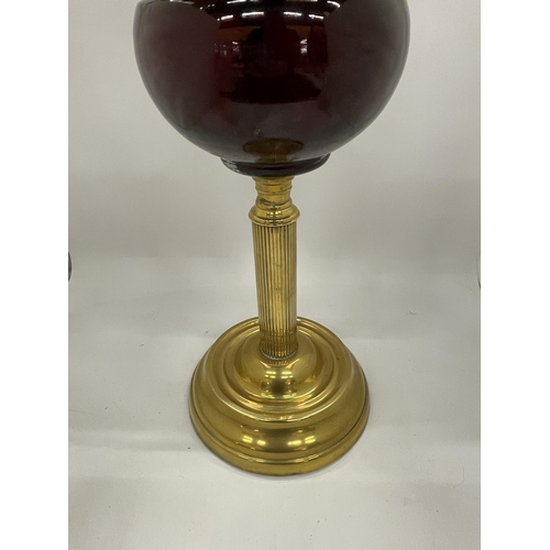 35 - AN EARLY TO MID 20TH CENTURY BRASS CORINTHIAN COLUMN OIL LAMP WITH CRANBERRY GLASS SHADE