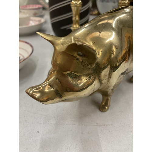 214 - A PAIR OF VINTAGE BRASS CANDLESTICKS AND A BRASS PIG MONEY BOX