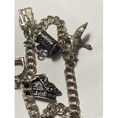 504 - A SILVER CHARM BRACELET WITH SIX CHARMS AND A HALLMARKED BIRMINGHAM HEART PADLOCK