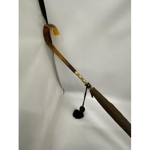 58 - A VINTAGE PARASOL WITH DECORATIVE YELLOW METAL FERRULE AND AMBER EFFECT HANDLE