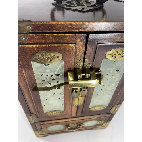 1 - A VINTAGE ORIENTAL HARDWOOD JEWELLERY BOX WITH BRASS FITTINGS AND JADE TYPE PANELLED DESIGN WITH INN... 