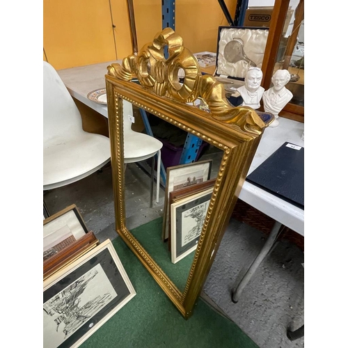 62 - AN ORNATE GILT FRAMED MIRROR WITH RIBBON DESIGN TOP