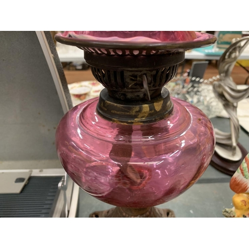 122 - A VINTAGE OIL LAMP WITH AN ORNATE BRASS BASE AND CRANBERRY GLASS SHADE HEIGHT APPROX 47CM