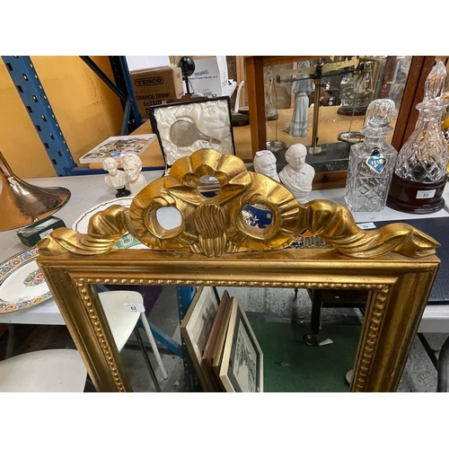 62 - AN ORNATE GILT FRAMED MIRROR WITH RIBBON DESIGN TOP