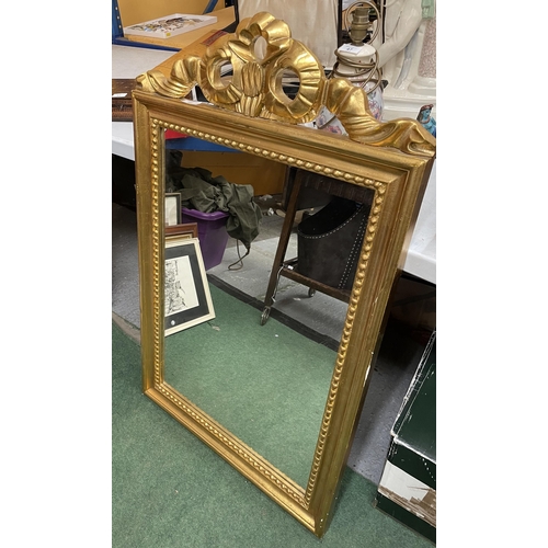 46 - AN ORNATE GILT FRAMED MIRROR WITH RIBBON DESIGN TOP