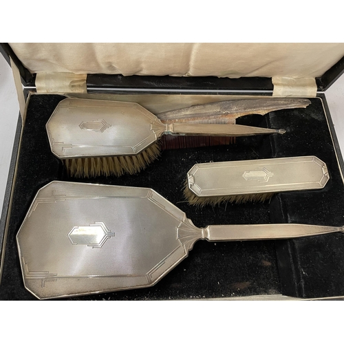 50 - AN ART DECO CASED HALLMARKED SILVER FOUR PIECE ENGINE TURNED DRESSING TABLE SET, TWO BRUSHES, MIRROR... 