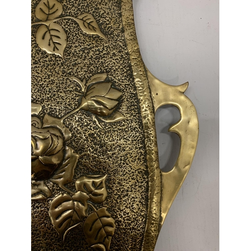 156 - A BRASS WALL HANGING IN THE SHAPE OF A SHIELD WITH FLORAL EMBOSSING 46CM X 34CM