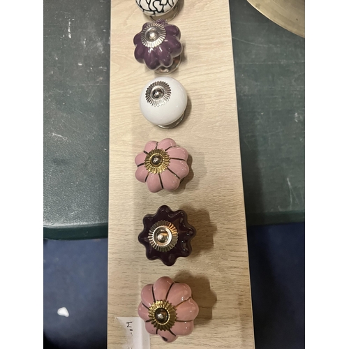 1096 - A QUANTITY OF MODERN DRAWER KNOBS ON A WOODEN BOARD