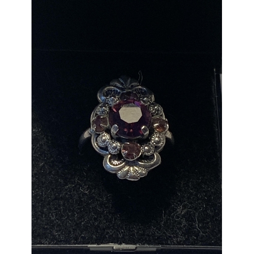 533 - A SILVER RING WITH A LARGE CENTRE PURPLE STONE IN A PRESENTATION BOX