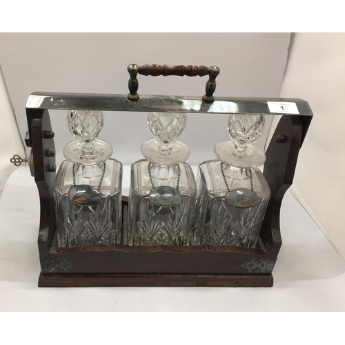 1 - A VINTAGE THREE BOTTLE TANTULUS WITH THREE CUT GLASS DECANTERS, ALL WITH HALLMARKED SILVER DECANTER ... 