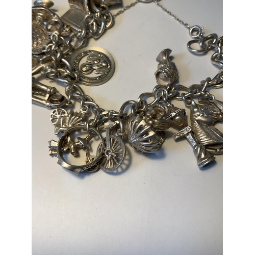 469 - A SILVER CHARM BRACELET WITH TWENTY CHARMS AND A HALLMARKED LONDON SILVER HEART CLASP