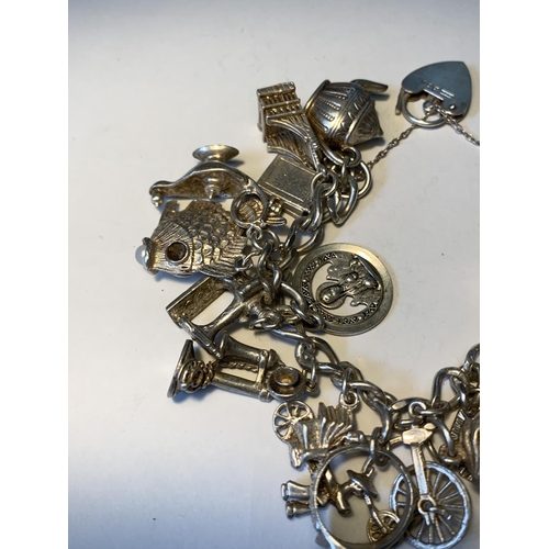 469 - A SILVER CHARM BRACELET WITH TWENTY CHARMS AND A HALLMARKED LONDON SILVER HEART CLASP