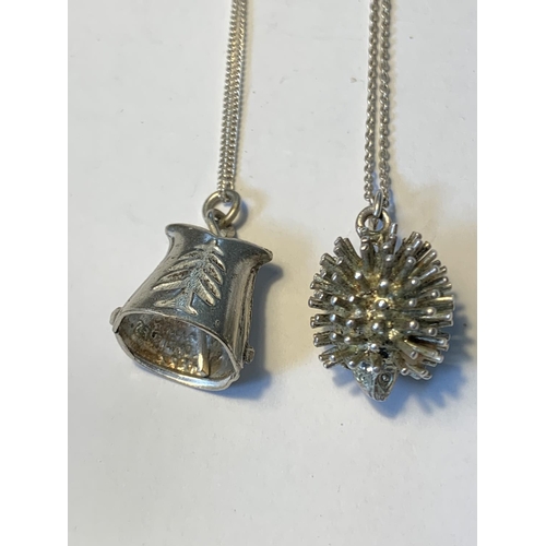 484 - TWO SILVER NECLACES WITH PENDANTS TO INCLUDE A HEDGEHOG AND A BELL