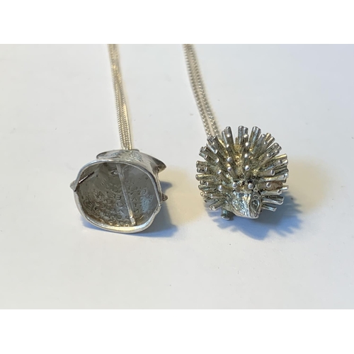 484 - TWO SILVER NECLACES WITH PENDANTS TO INCLUDE A HEDGEHOG AND A BELL