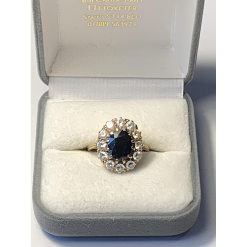 620 - A 9 CARAT GOLD RING WITH A LARGE CENTRE SAPPHIRE SURROUNDED BY TWELVE CLEAR STONES SIZE Q/R IN A PRE... 