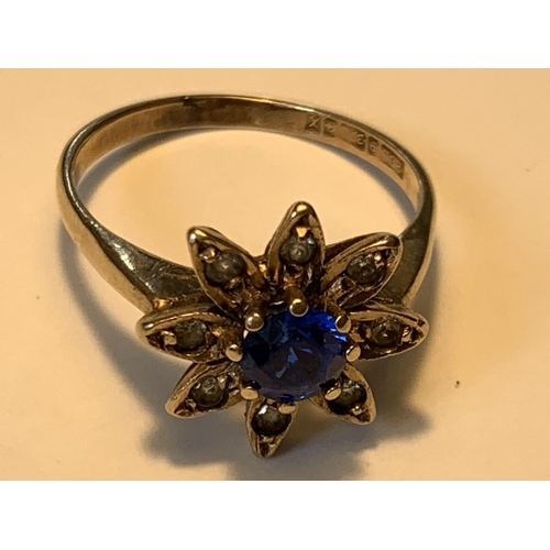 650 - A 9 CARAT GOLD RING WITH A CENTRE BLUE STONE AND CUBIC ZIRCONIAS IN A FLOWER DESIGN SIZE N