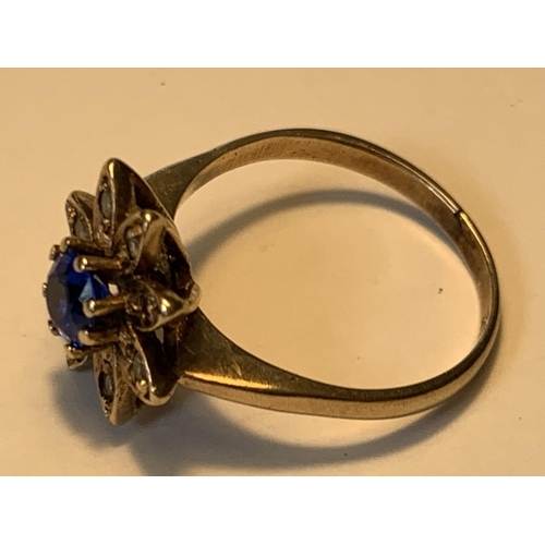 650 - A 9 CARAT GOLD RING WITH A CENTRE BLUE STONE AND CUBIC ZIRCONIAS IN A FLOWER DESIGN SIZE N