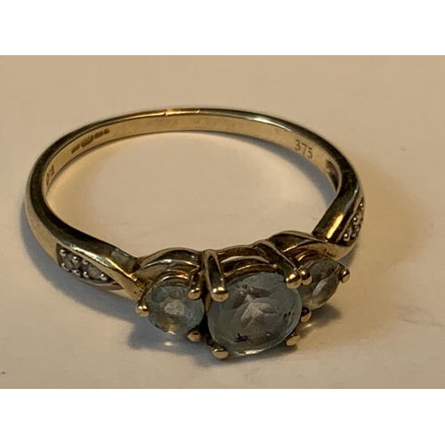 652 - A 9 CARAT GOLD RING WITH THREE IN LINE AQUA MARINES AND DIAMONDS TO THE SHOULDERS SIZE L