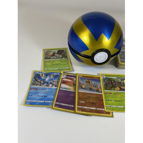 105 - A POKEMON BALL TIN CONTAINING ASSORTED POKEMON CARDS, HOLOS, RARES ETC