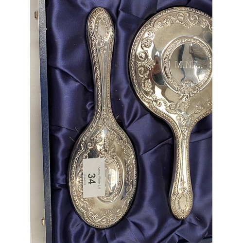 34 - A CASED HALLMARKED SILVER BACKED THREE PIECE DRESSING SET COMPRISING COMB, MIRROR AND BRUSH