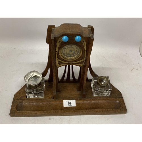 59 - AN ARTS AND CRAFTS WOODEN CLOCK WITH INSET INKWELLS